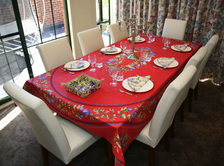8 seater French provincial tablecloth with oval designs of figs on a red background.